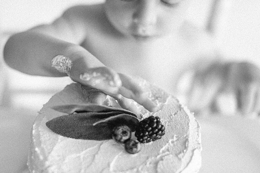 Black and white image of baby boy eating cake.