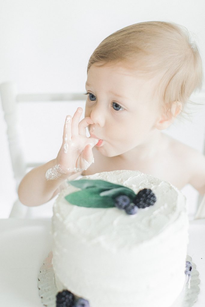 Boy in high chair eating cake.