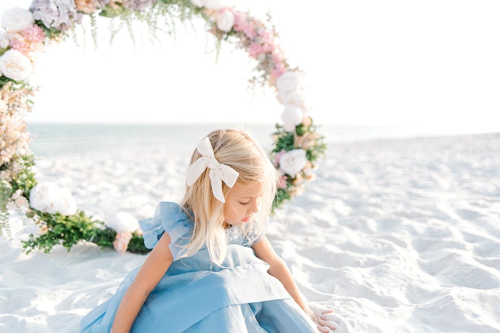 little girl in blue dress on the beach with a floral hoop