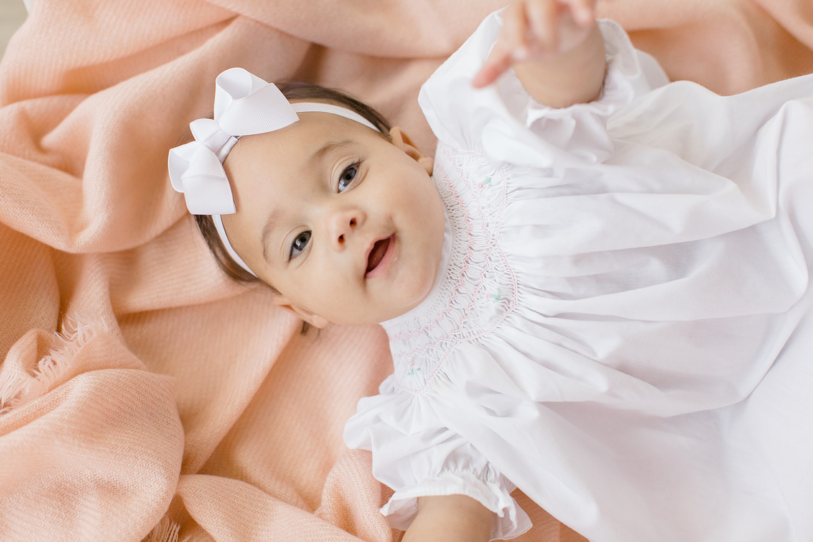 Baby sits happily in a well-lit studio during a milestone photography session. The soft, neutral backdrop highlights the baby's joyful expressions, while simple, timeless props add warmth to the scene. Captured by a Memphis baby photographer, the session focuses on preserving this sweet stage of childhood in a clean, classic style.